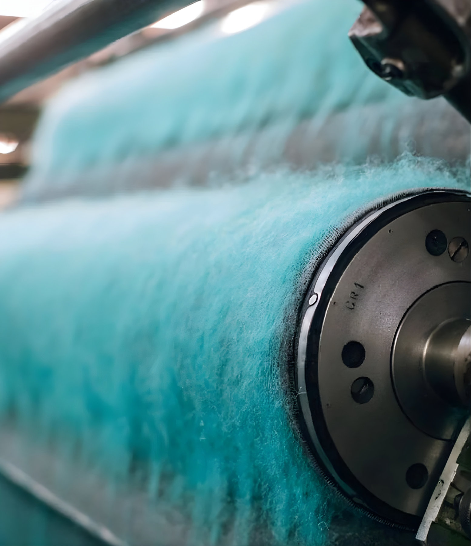 Close-up of teal wool fibres being processed on a carding machine for Harris Tweed production